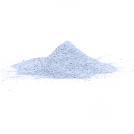 A small conical pile of fine, light blue powder sits on a smooth, white surface, against a plain white background.