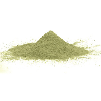 Green powder forming a small mound, resting on a flat, white surface, with dispersed fine particles around it.
