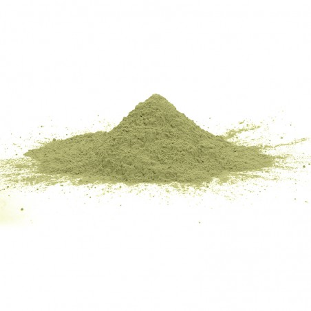 Groen poeder vormt een kleine heuvel, rustend op een vlak, wit oppervlak, met verspreide fijne deeltjes eromheen.