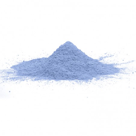 Un petit tas de poudre bleu pâle repose sur une surface blanche, suggérant un environnement de laboratoire calme et propre.