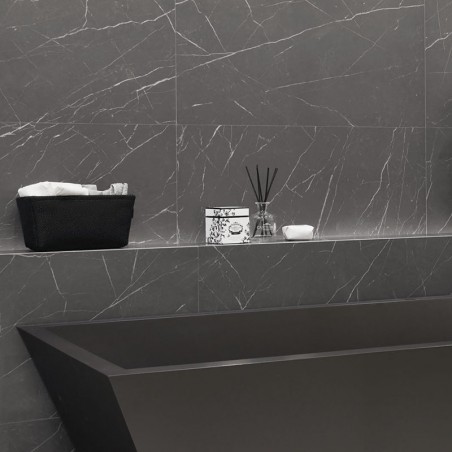 An grauen Marmorwänden steht eine schwarze rechteckige Badewanne. Darüber befindet sich auf einem Regal ein Korb mit Handtüchern