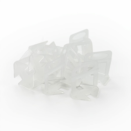 Transparent plastic bag clips are scattered haphazardly on a plain white background, forming a loosely connected pile.