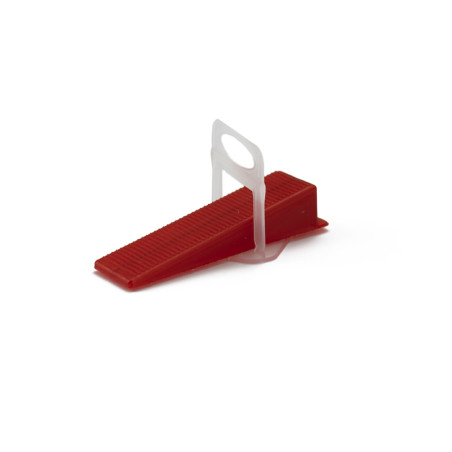 A red plastic wedge lies angled on a flat surface. a small white handle protrudes vertically from its center, surrounded by a pl