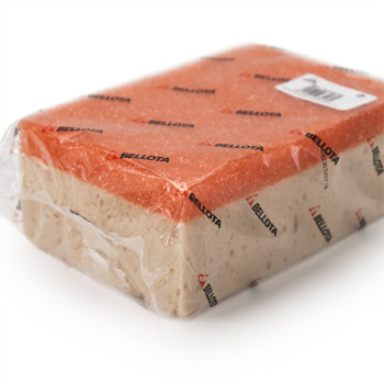 Une éponge de nettoyage rectangulaire enveloppée dans du plastique transparent avec des côtés rouges et beiges, recouverte du te