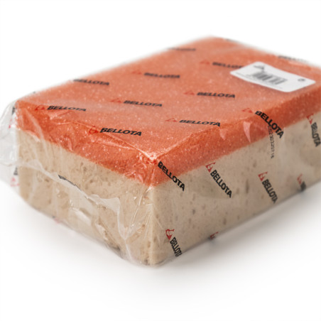 Une éponge de nettoyage rectangulaire enveloppée dans du plastique transparent avec des côtés rouges et beiges, recouverte du te
