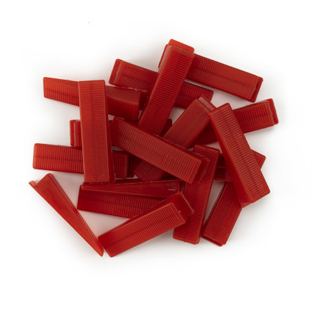 Red rectangular combs are stacked in a scattered pile on a plain white surface.