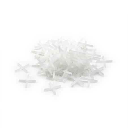 A pile of white plastic tile spacers forms a loose mound against a plain white background.