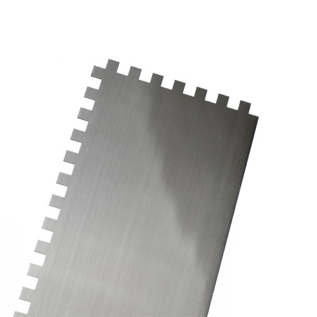 A metal notched trowel with evenly spaced square teeth, designed for spreading adhesive, is positioned against a plain white bac