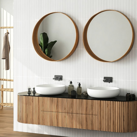 Deux miroirs ronds réfléchissant la lumière sont suspendus au-dessus d'une vanité moderne à texture de bois. Des lavabos blancs 