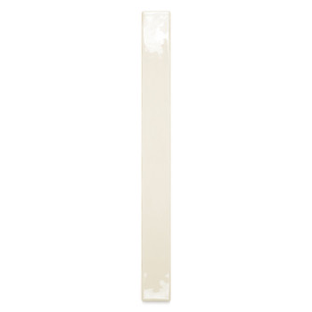 Un carreau de céramique étroit de couleur crème repose verticalement sur un fond blanc, réfléchissant subtilement la lumière sur