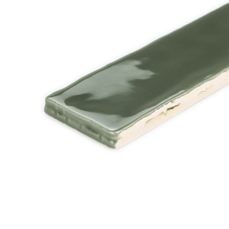 Un carreau rectangulaire vert brillant repose avec sa surface lisse réfléchissant la lumière, entourée d'un fond blanc uni.