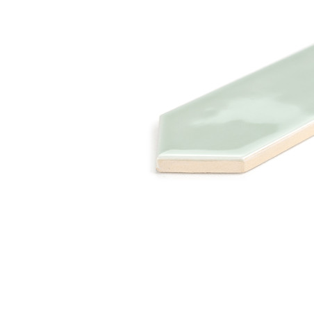 Um ladrilho verde-menta hexagonal brilhante com uma borda chanfrada fica inclinado sobre um fundo branco liso, refletindo leveme