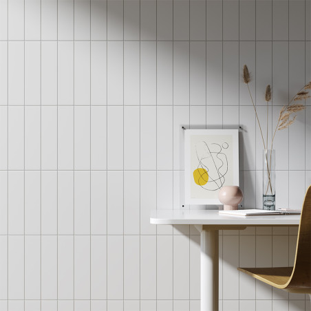 Una pared de azulejos blancos proporciona un telón de fondo elegante para un espacio de trabajo minimalista, con un dibujo abstr