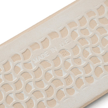 Een beige rubberen zool heeft een verhoogd, in elkaar grijpend geometrisch patroon met de tekst `MADE IN U.S.A.` reliëf in het m