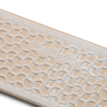 Superficie con textura beige con semicírculos superpuestos en relieve que muestran `MADE IN SPAIN`, lo que sugiere artesanía en 