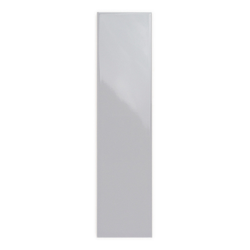 Um ladrilho retangular brilhante fica verticalmente, refletindo sutilmente a luz, colocado contra um fundo branco liso.