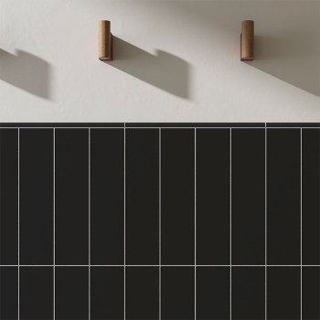 Des carreaux rectangulaires sombres sont disposés selon un motif en grille contre un mur lisse et clair. Deux crochets en bois p