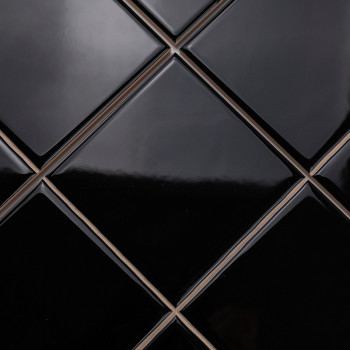 Ladrilhos pretos brilhantes em forma de diamante são dispostos em um padrão elegante e repetitivo, criando uma superfície elegan