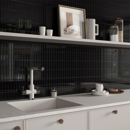 Uma bancada de cozinha minimalista apresenta uma torneira e pia modernas, tendo como pano de fundo azulejos pretos brilhantes co