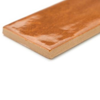 Un carreau rectangulaire brun brillant se trouve avec son bord visible sur un fond blanc, mettant en valeur sa surface lisse et 