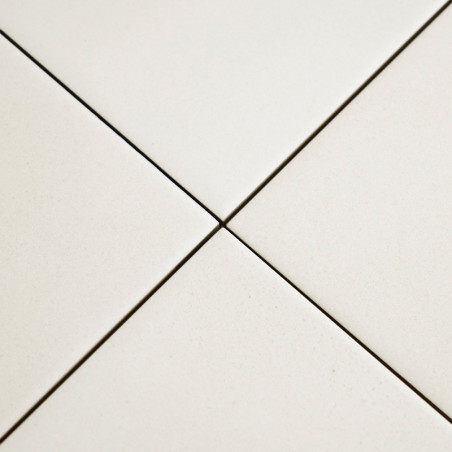 Quatre carreaux de céramique blanche se rejoignent en un point central, formant une forme en plus avec des lignes de coulis étro