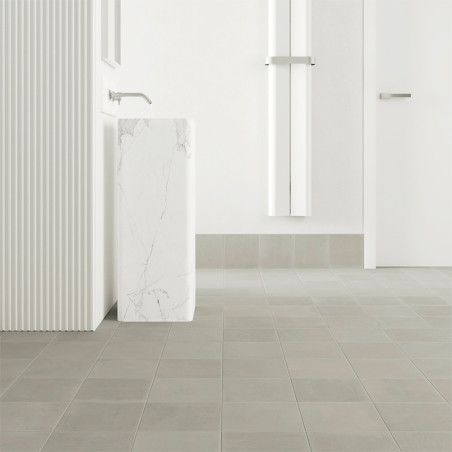 Des carreaux carrés recouvrent le sol d'une salle de bains minimaliste, comprenant un lavabo sur colonne en marbre élégant avec 