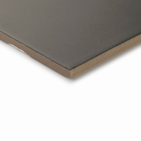 A smooth, dark-colored tile lies flat on a light surface, showcasing its sharp, clean edges and uniform thickness in a minimalis