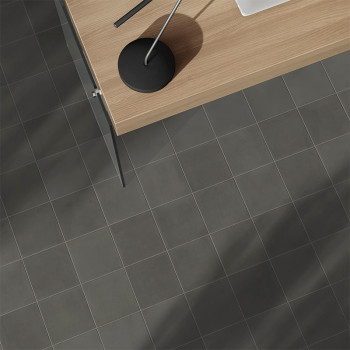 A gray tiled floor sits beneath a modern wooden desk with a sleek black lamp, creating a minimalist office atmosphere.