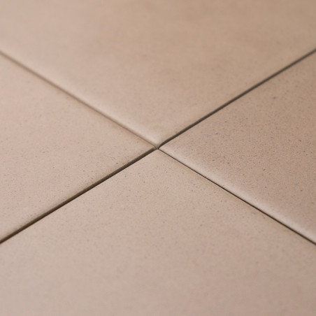 Vier beige tegels kruisen elkaar netjes en vormen op de hoeken een klein kruis. Ze bevinden zich op een vlak, effen oppervlak.