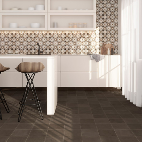Two bar stools stand by a white kitchen island. behind is a geometric-patterned tile backsplash. Sunlight streams through a shee