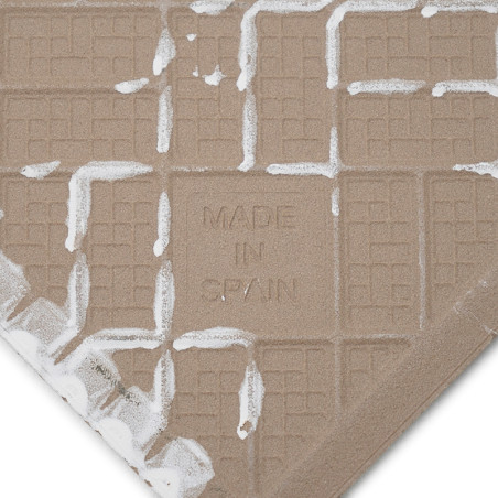 Een beige tegel met de opdruk MADE IN SPAIN heeft een wafelachtig rasterpatroon. Witte, getextureerde resten bedekken gedeelteli