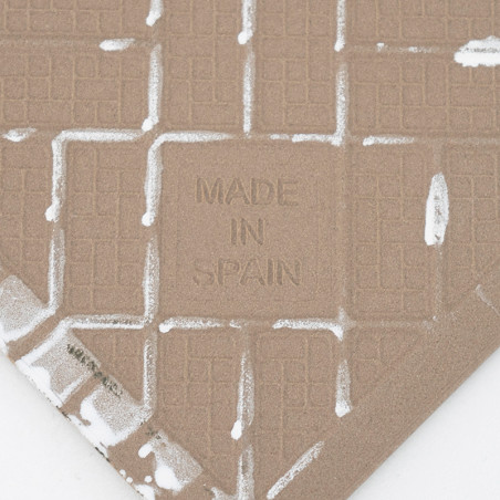 Op een getextureerde keramische tegel zijn in het midden de woorden `MADE IN SPAIN` in reliëf weergegeven, met een rasterpatroon