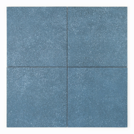 Quatre carreaux de céramique carrés bleus avec une texture mouchetée disposés selon un motif en grille, formant une disposition 