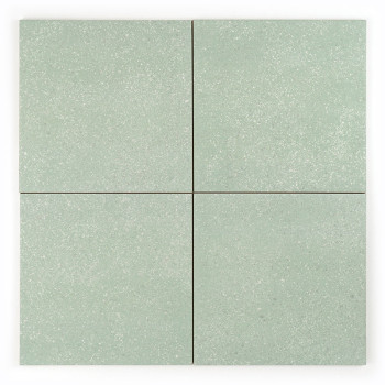 Un azulejo cuadrado muestra una sutil textura moteada, con un tono verde suave, que crea una apariencia neutra y relajante.