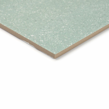 Um ladrilho cerâmico salpicado de verde assenta sobre um fundo branco, mostrando sua superfície lisa e polida e bordas angulares