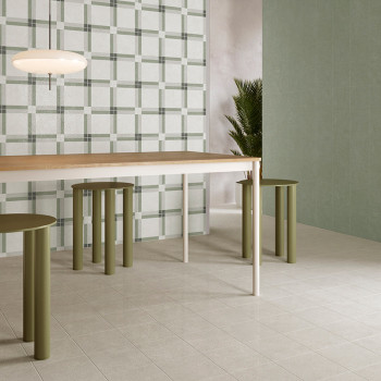 Uma mesa de jantar moderna com bancos cilíndricos verdes fica sobre um piso de azulejos claros, cercada por azulejos lisos e com