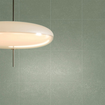 Uma luz de teto redonda e branca está pendurada em uma parede lisa e de azulejos verdes, lançando um brilho quente sobre a super