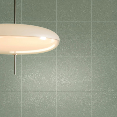 Uma luz de teto redonda e branca está pendurada em uma parede lisa e de azulejos verdes, lançando um brilho quente sobre a super