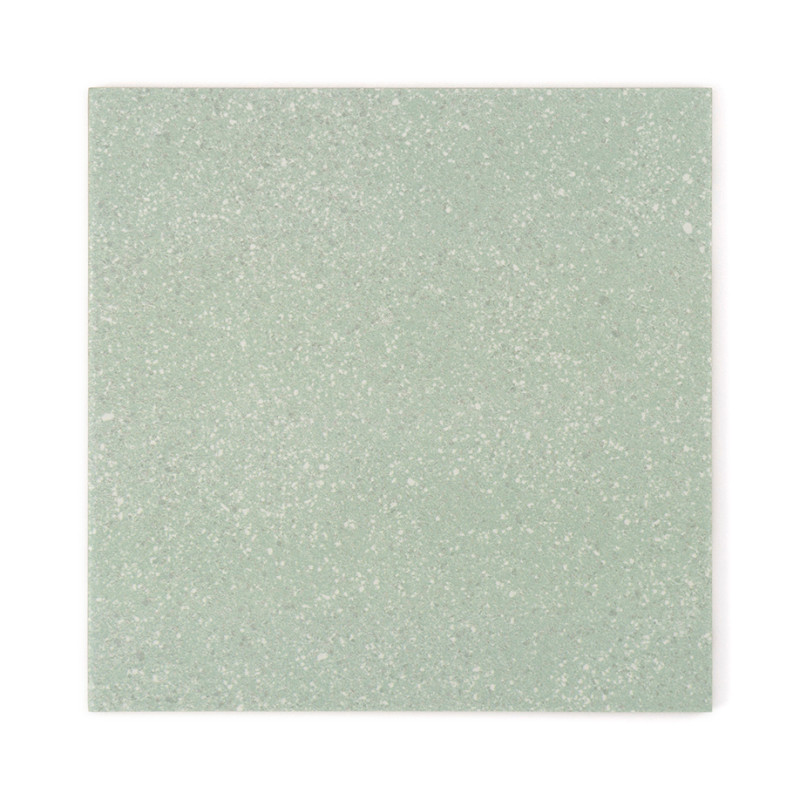 Un azulejo cuadrado muestra una sutil textura moteada, con un tono verde suave, que crea una apariencia neutra y relajante.