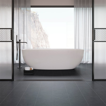 Une baignoire autoportante blanche est centrée dans une salle de bains minimaliste aux carreaux noirs, encadrée par de grandes f