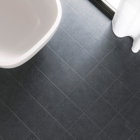 Des carreaux carrés gris foncé forment un motif en grille sur le sol d'une salle de bains, à côté d'une baignoire blanche et d'u