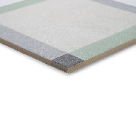Un azulejo cerámico presenta una superficie clara texturizada con un patrón de borde verde y gris, mostrada desde una perspectiv