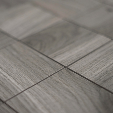Des carreaux rectangulaires gris sont disposés, alignés selon un motif en grille, avec une texture semblable à du bois suggérant