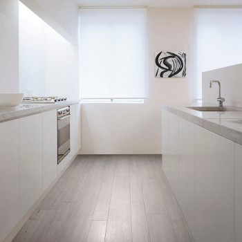 Eine moderne Küche verfügt über elegante weiße Schränke und Arbeitsplatten mit einem grauen Fliesenboden mit Holzstruktur und sa