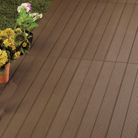 Brown, ribbed tiles form a patio. bordered by green grass and colorful potted flowers adding decorative contrast to the outdoor 