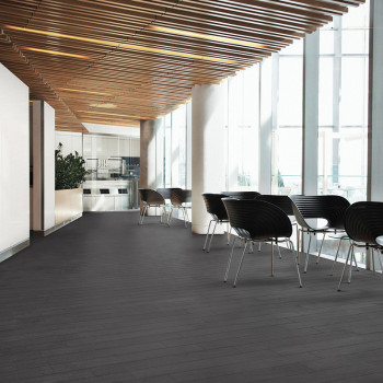 Des chaises bordent un couloir élégant et moderne avec un sol carrelé sombre et un plafond à lattes en bois contre de grandes fe