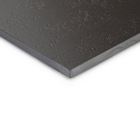 Un carreau lisse et noir avec une surface texturée repose sur une surface plane, soulignant ses bords fins et sa finition mate.