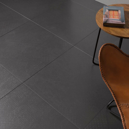 Dark gray square tiles form a smooth floor. A brown leather chair sits near a round wooden side table with a magazine.