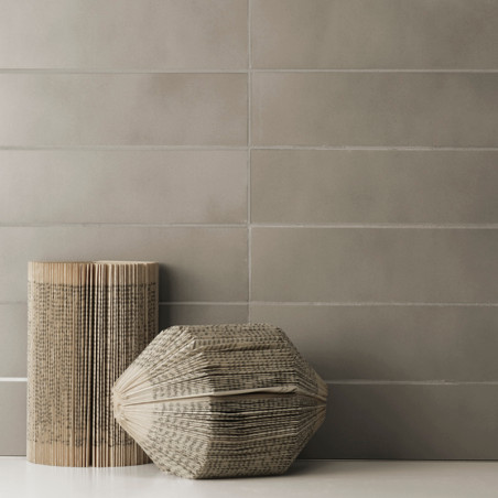 Les carreaux gris rectangulaires forment une toile de fond murale lisse et uniforme. Deux objets sculptés en forme de livre avec