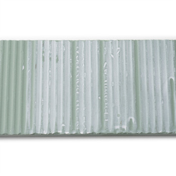 Un carreau texturé rectangulaire présente des rainures verticales et une teinte vert pâle avec un texte pâle : « CUMEL CA 45 HEL